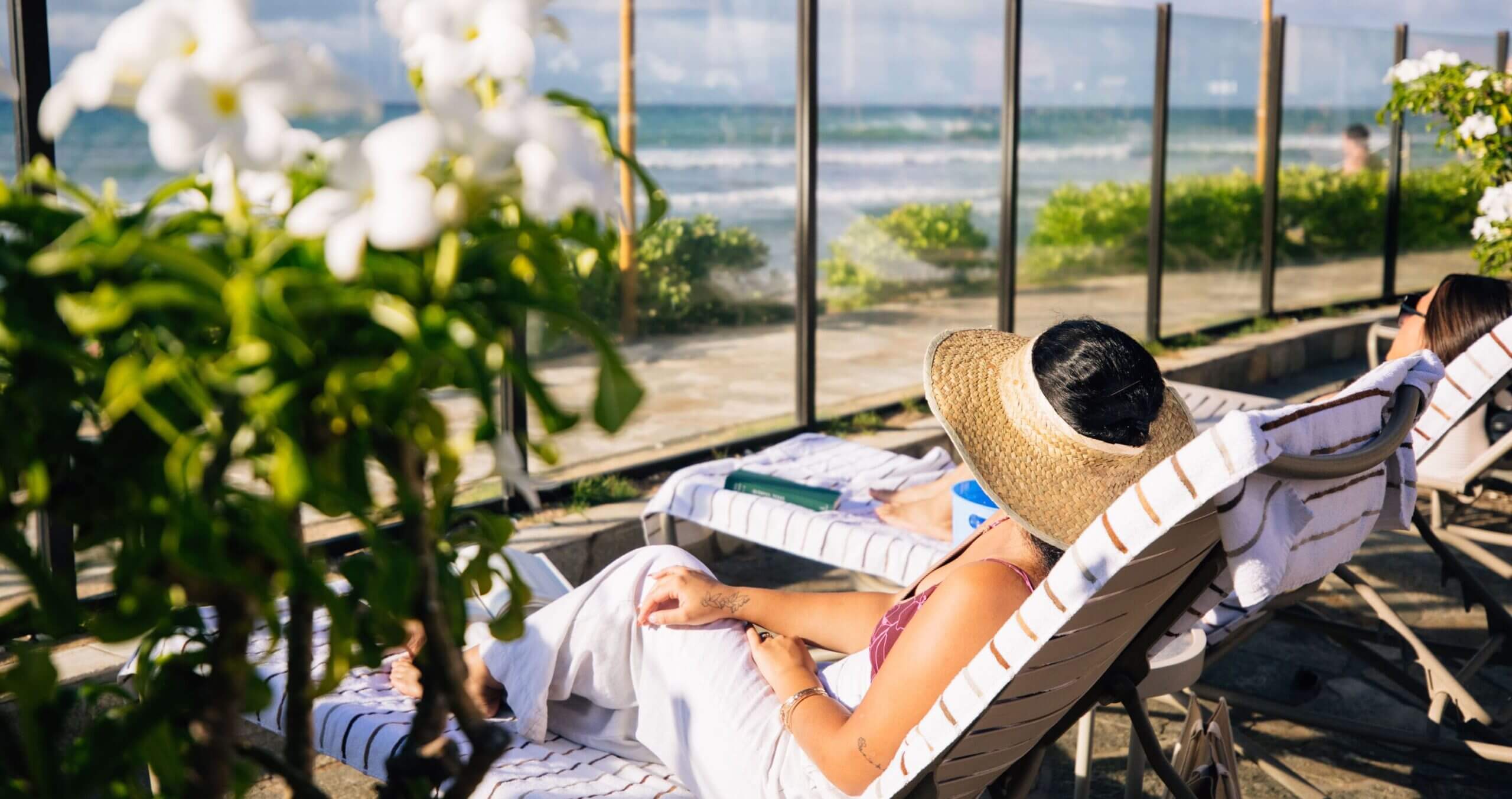 2 women relaxing on loungers with oceanfront views.