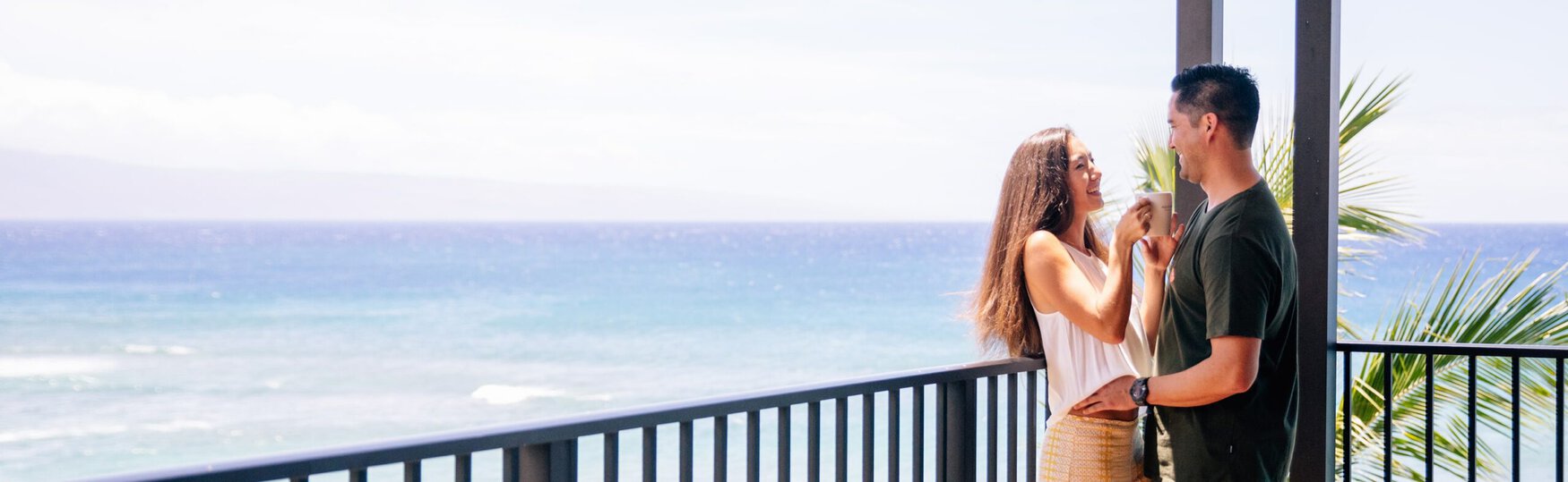 Couple standing on a balcony that overlooks the ocean.